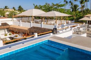 a pool at a resort with umbrellas and tables at Pousada Chez Toi in Jericoacoara