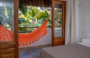 a bedroom with an orange hammock in front of a window at Pousada Chez Toi in Jericoacoara