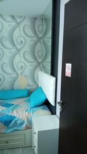 ein Schlafzimmer mit einem Bett mit blauen Kissen und einer Tür in der Unterkunft Aliston Papilio Apartment in Ngawinan