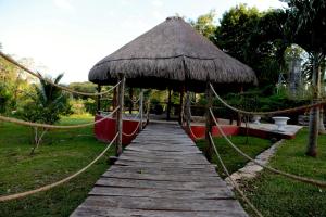 un camino de madera que conduce a una cabaña con techo de hierba en Hacienda San Jose Poniente, en Hoctún