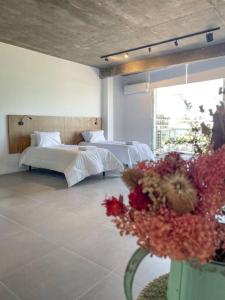 1 dormitorio con 2 camas y un jarrón de flores en Departamento premium en Pilar 227 en Manuel Alberti