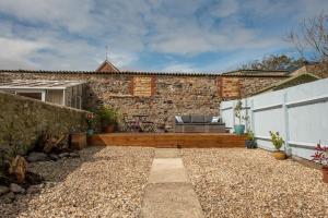 a patio with a bench and a stone wall at Seashells, close to seafront, large private garden in Lyme Regis
