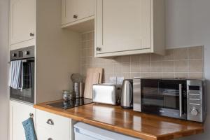 a kitchen with a wooden counter top with a microwave at Seashells, close to seafront, large private garden in Lyme Regis