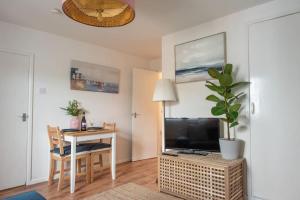 a living room with a desk with a television and a table with a plant at Seashells, close to seafront, large private garden in Lyme Regis