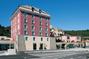 a tall pink building on the side of a street at Sea Art Hotel in Vado Ligure
