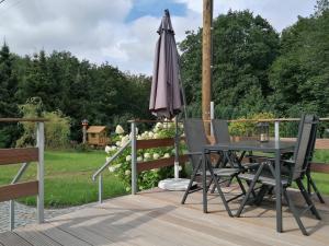 einen Regenschirm, einen Tisch und Stühle auf einer Terrasse in der Unterkunft Käthes Sommerhaus in Schöna