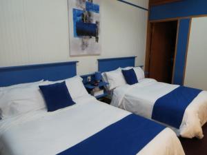two beds in a room with blue and white at Motel Magistral in St-Raphael-de-Bellechasse