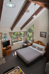 a bedroom with a bed and a tv and some windows at Howick Motor Lodge in Auckland