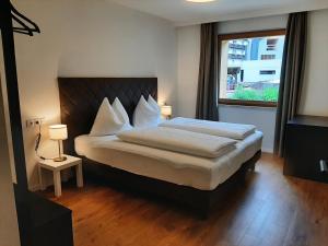 a bedroom with a large bed and a window at Tyrol Living & Cafe in Nova Levante