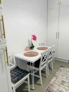 uma mesa de jantar branca com cadeiras brancas e um vaso com flores em Luxury Queen em Câmpulung Moldovenesc