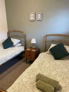 a bedroom with two beds and a table with a lamp at The Potting Shed in Bredon