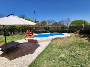 uma piscina com um guarda-sol e um banco e um guarda-sol em Casa Conteiner em Salta