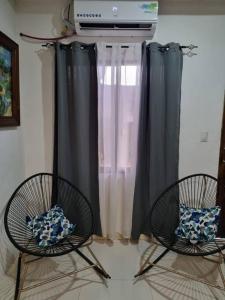 two chairs in front of a window with curtains at Pura vida apartament 5 min near aiport NO PARKING SITE in Alajuela