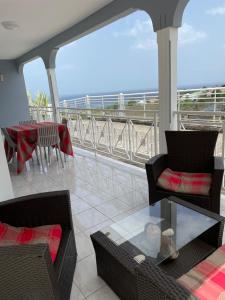een balkon met stoelen en een tafel en uitzicht op de oceaan bij Villa de L'anse - bas de villa in Vieux-Habitants