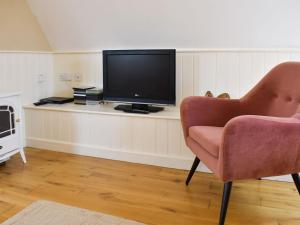a living room with a tv and a chair at Goodwood Coach House in Westhampnett