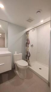 a white bathroom with a toilet and a shower at Beautiful 2 bedroom + office basement suite in Calgary