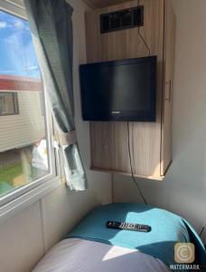a tv on the corner of a room with two remote controls at Robin hood Caravan park North Wales Free Wi-Fi and Smart TVs Passes not included in Rhyl
