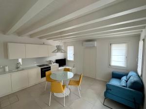 a kitchen and living room with a blue couch and a table at Alla Torre 735 - Stay Local Burano in Burano