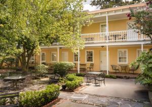 zewnętrzny widok na żółty dom ze stołami i krzesłami w obiekcie The Jasmine House w mieście Charleston