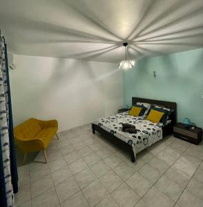 een slaapkamer met een bed en een stoel bij Villa de L'anse - bas de villa in Vieux-Habitants