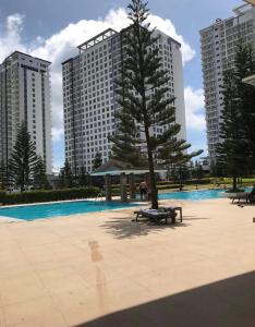 ein Baum in der Mitte eines Pools mit hohen Gebäuden in der Unterkunft A&B Condo with Netflix at SMDC Wind Residences in Tagaytay