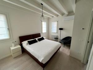 1 dormitorio blanco con 1 cama y 1 silla en Alla Torre 735 - Stay Local Burano, en Burano
