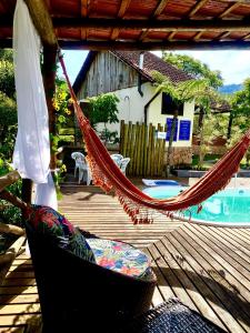 a hammock on a deck next to a pool at Pousada Magia da Montanha in Visconde De Maua