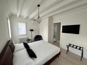 - une chambre avec un lit blanc et une télévision à écran plat dans l'établissement Alla Torre 735 - Stay Local Burano, à Burano