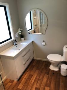 uma casa de banho com um lavatório, um WC e um espelho. em Tranquil Family Retreat em Akaroa