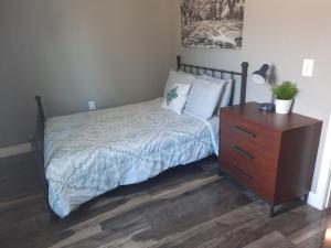 ein Schlafzimmer mit einem Bett mit einer Holzkommode und einem Nachttisch in der Unterkunft Downtown Bungalow- 2 bedroom in Cedar City