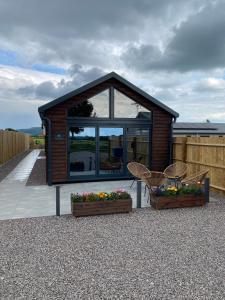 uma pequena casa com duas cadeiras e flores em frente em The Potting Shed em Bredon