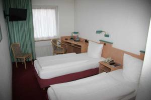 a hotel room with two beds and a desk at Vorsfelder Hof in Wolfsburg