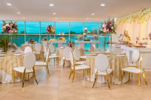 un salón de banquetes con mesas, sillas y flores en Hotel Ciudad de David, en David