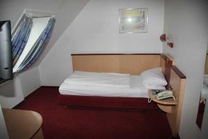 ein kleines Schlafzimmer mit einem Bett und einem Telefon in der Unterkunft Vorsfelder Hof in Wolfsburg