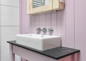 a white sink in a bathroom with a mirror at Gwêl y Môr in Abersoch