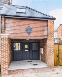 a brick house with a black garage door at Centrally situated house plus private parking in Cheltenham