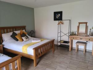 a bedroom with a bed and a table and a mirror at Bumble Barn Bed & Breakfast in North Walsham