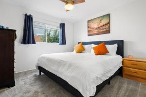 - une chambre avec un grand lit blanc et des oreillers orange dans l'établissement The Green Haven, 1 Minute Walk to the Beach and Restaurants, King Beds, Beach Amenities, à Ventura