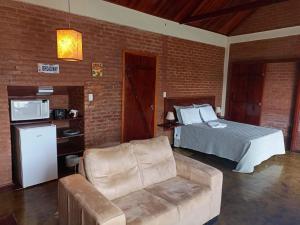 ein Schlafzimmer mit einem Bett und einem Sofa in einem Zimmer in der Unterkunft Chalé Recanto do Sol in Paraisópolis