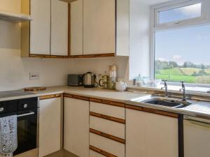 a kitchen with a sink and a window at Airdside Cottage in Crossmichael