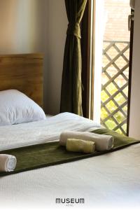 łóżko z dwoma ręcznikami na nim obok okna w obiekcie Museum Hotel w Prisztinie
