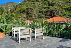 two chairs and a table on a balcony with a mountain at Casa da Praia, a Home in Madeira in Ribeira Brava