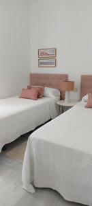 a bedroom with two beds and a table with a lamp at El 2 de Flamenco Ático 3ºA in Cádiz