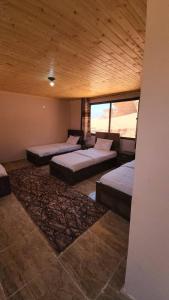 una camera con 4 letti in una stanza con soffitto in legno di Wadi Rum Desert Lovers Camp a Wadi Rum