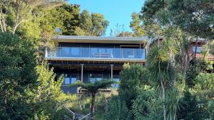 a house on the side of a hill with trees at Paihia Central Apartments in Paihia