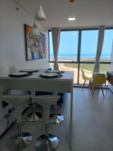 a kitchen with a table and chairs with a view of the ocean at FLAT BEIRA MAR BARRA DE JANGADA RECIFE ANDAR ALTO in Recife