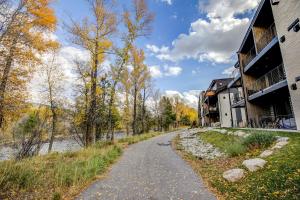 a dirt road next to a building next to a river at River West Ptarmigan Peak Condo - Upscale Riverfront Retreat in Silverthorne