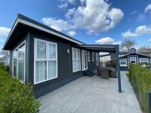 een zwart huis met witte ramen en een patio bij Luxus Chalet im schönen Recratiepark De Veerstal in Rheden