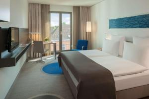 een hotelkamer met een bed, een bureau en een televisie bij Dorint Hotel Hamburg-Eppendorf in Hamburg