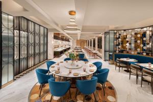 une salle à manger avec une grande table et des chaises bleues dans l'établissement Radisson Mumbai Goregaon, à Mumbai